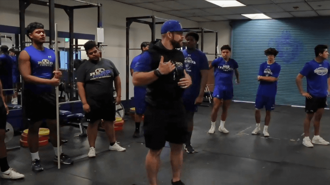 Coach spotting an athlete during a lift in a school weight room